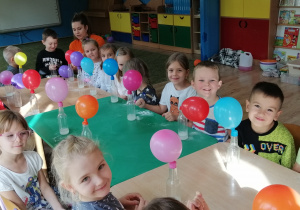 Dzieci obserwują nadmuchane w wyniku reakcji chemicznej balony